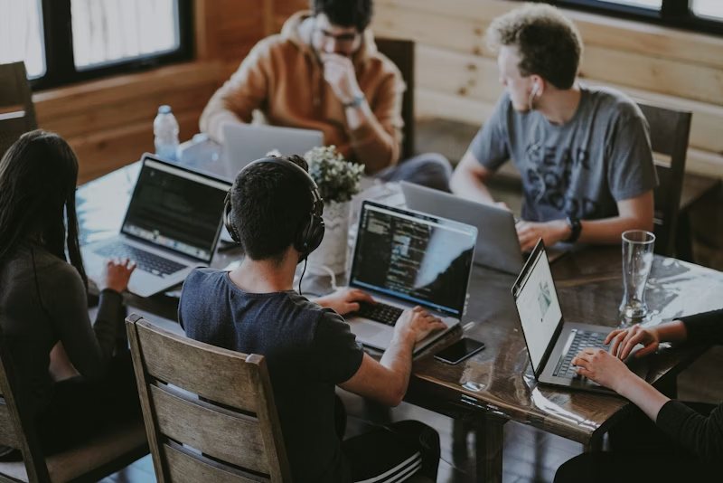 Equipo de trabajo colaborando con computadoras portátiles en una mesa